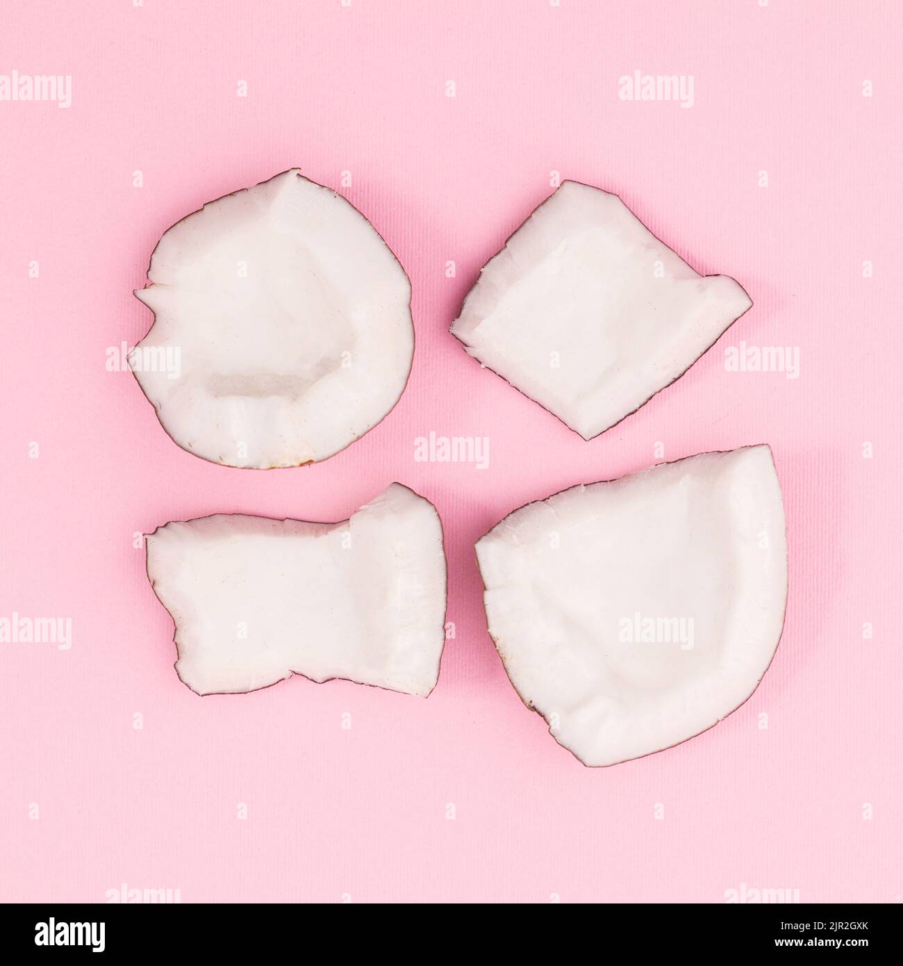Frisch geschnittene Kokosnuss auf pastellrosa Hintergrund. Flach liegend Stockfoto