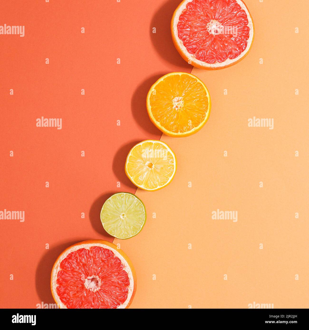 Zwei Schatten orange Hintergrund mit geschnittenen Zitrusfrüchten in Reihe. Sommerliches Obst-Konzept. Flach liegend Stockfoto