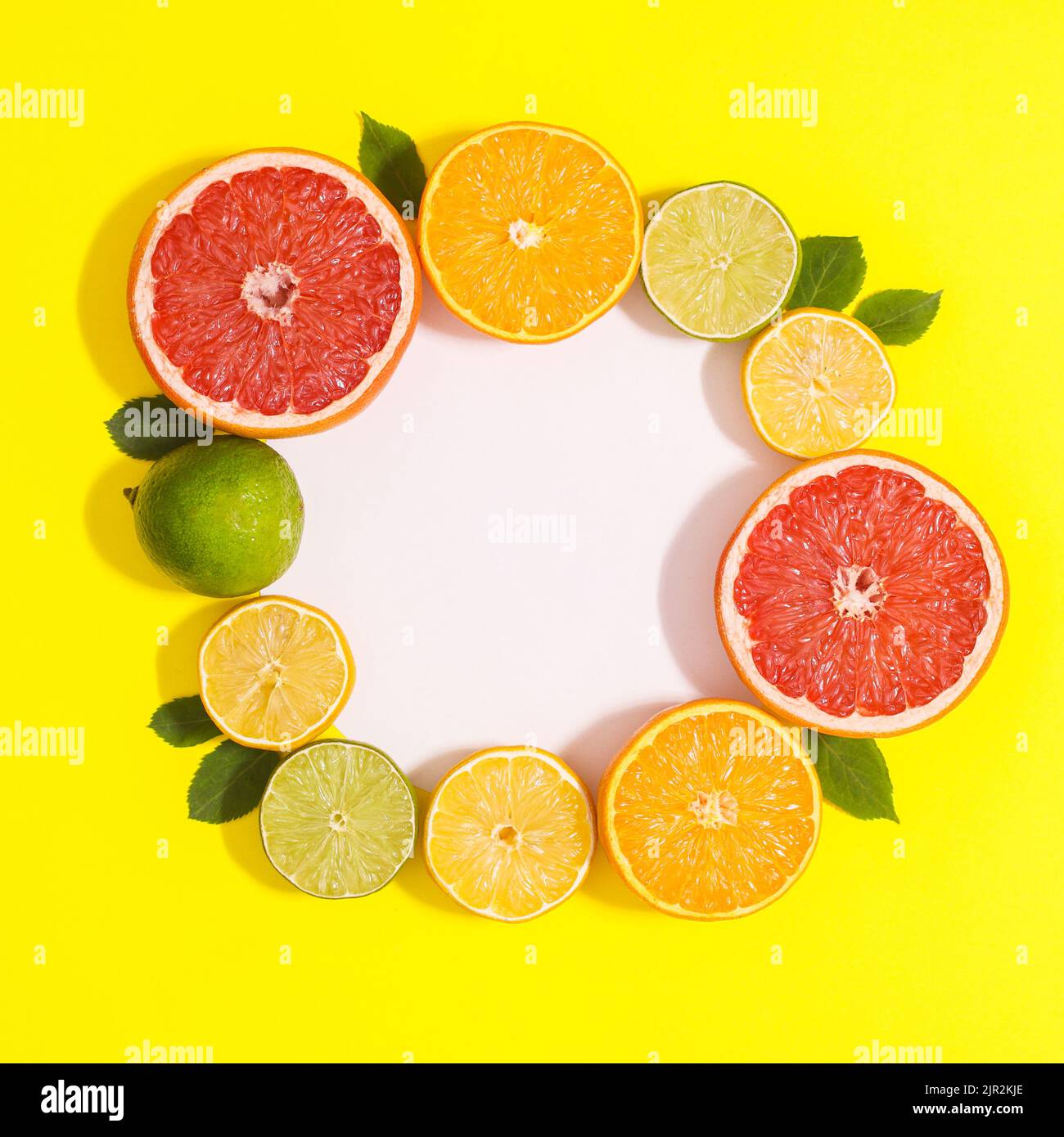 Kreativer Copy Space Frame mit Zitrusfrüchten auf gelbem Hintergrund. Flach liegend Stockfoto