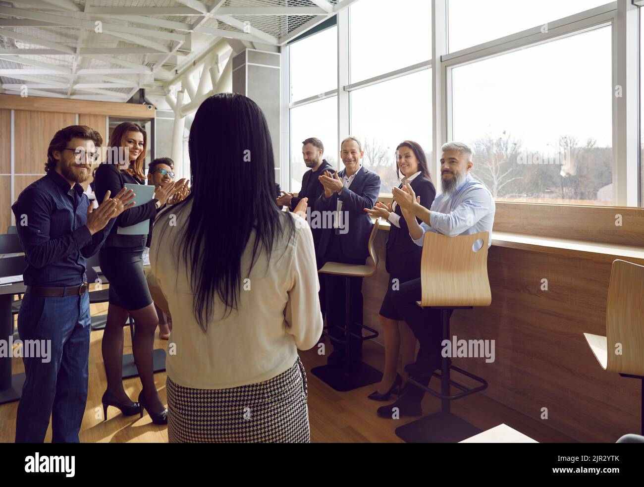 Freudig zufriedene Geschäftsleute applaudieren ihrer Kollegin bei der Teambesprechung im Büro. Stockfoto