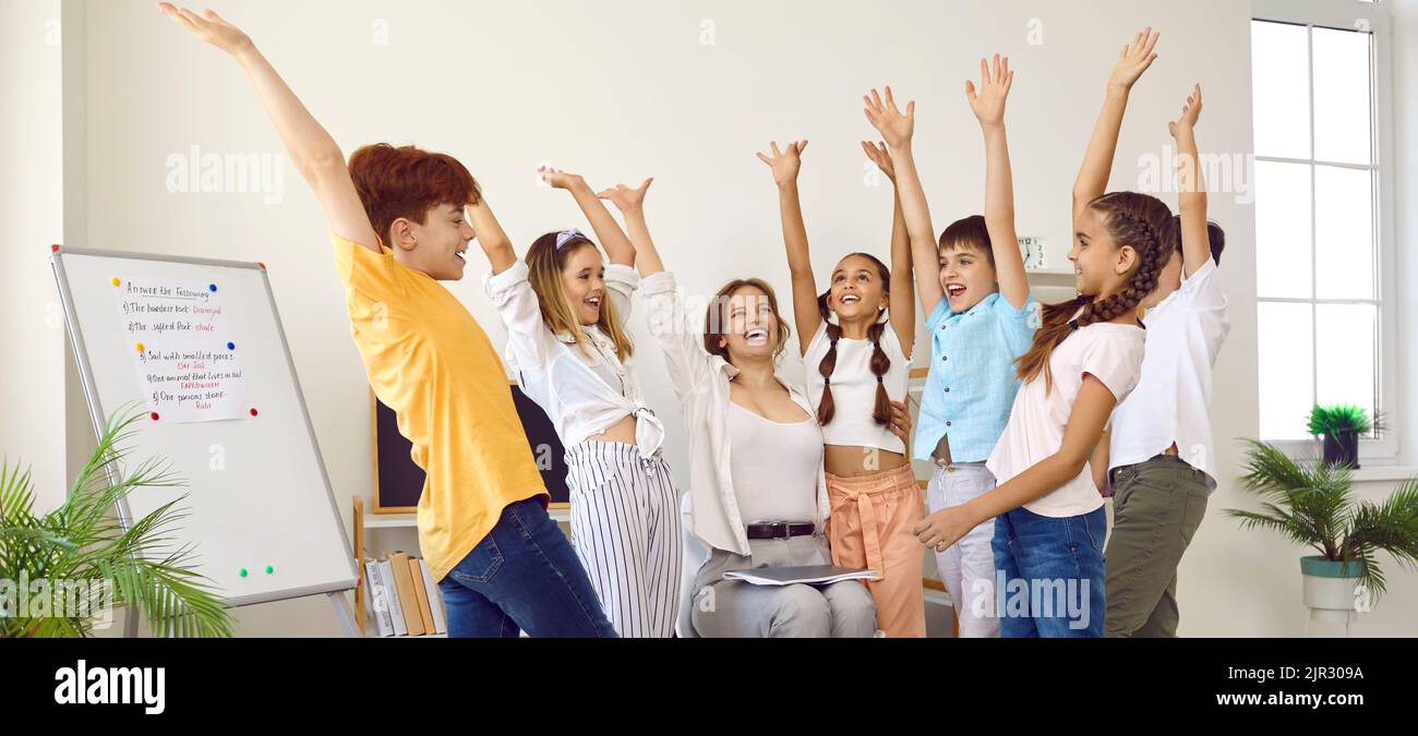 Eine Gruppe von Grundschülerinnen und -Schülern und deren Lehrer, die ihre Hände hochheben und den Geist der Einheit spüren. Stockfoto