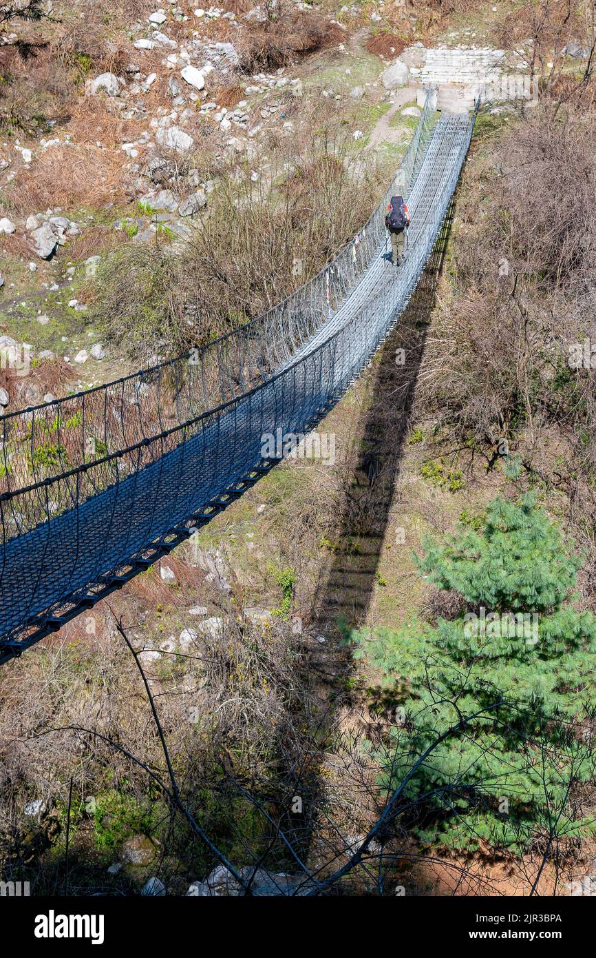 Eine vertikale Aufnahme eines Wanderers, der auf der Hängebrücke im Dorf Tal, Dharapani, Nepal, läuft Stockfoto