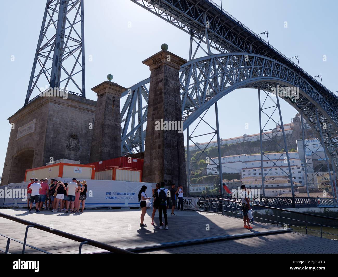 An einem Sommertag versammeln sich Touristen unter der Brücke Luís i im Schatten. Porto, Portugal Stockfoto