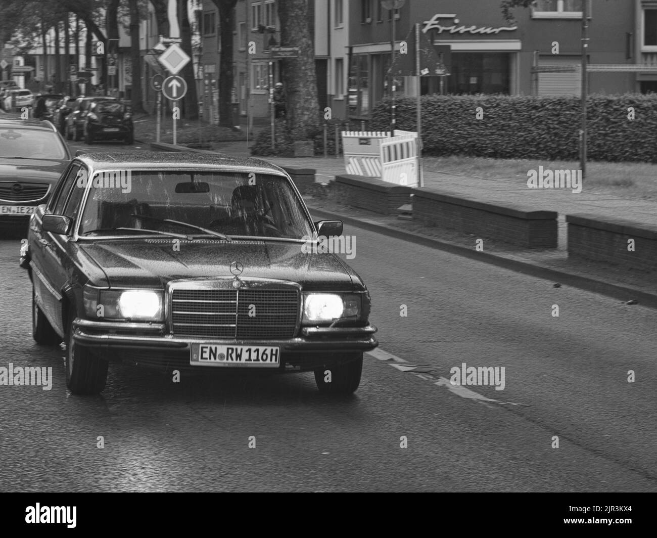 Eine Graustufenaufnahme eines Classic Mercedes S Klasse, der an einem regnerischen Tag auf den Straßen Bochums unterwegs ist Stockfoto