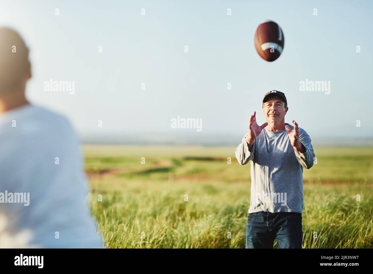 Fußball ist etwas, das sie wirklich verbinden. Vater fangen einen Fußball von seinem Sohn auf einem Feld. Stockfoto