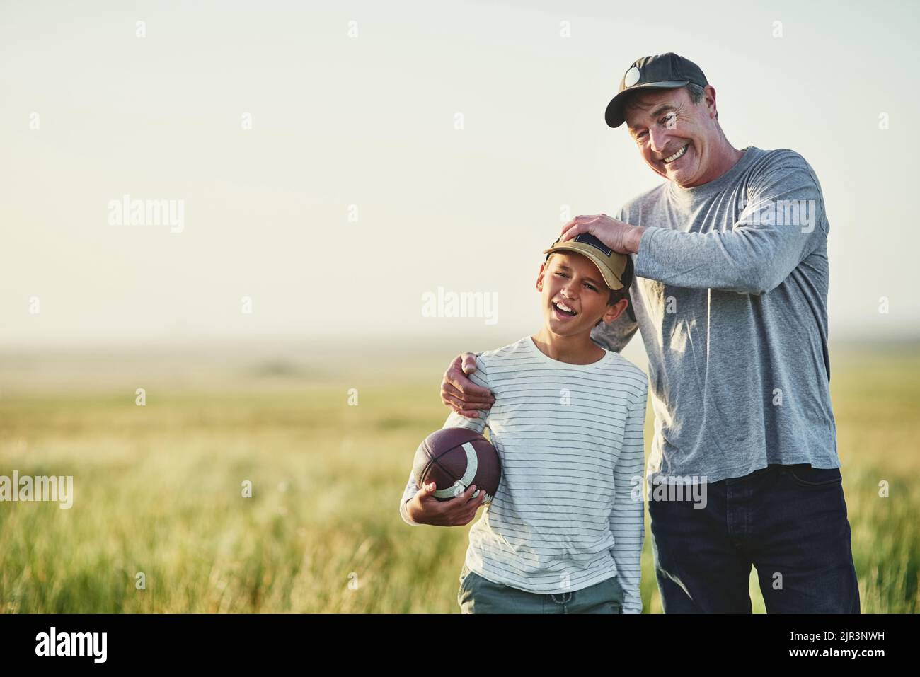Vater und Sohn spielen mit einem Fußball auf einem Feld. Stockfoto