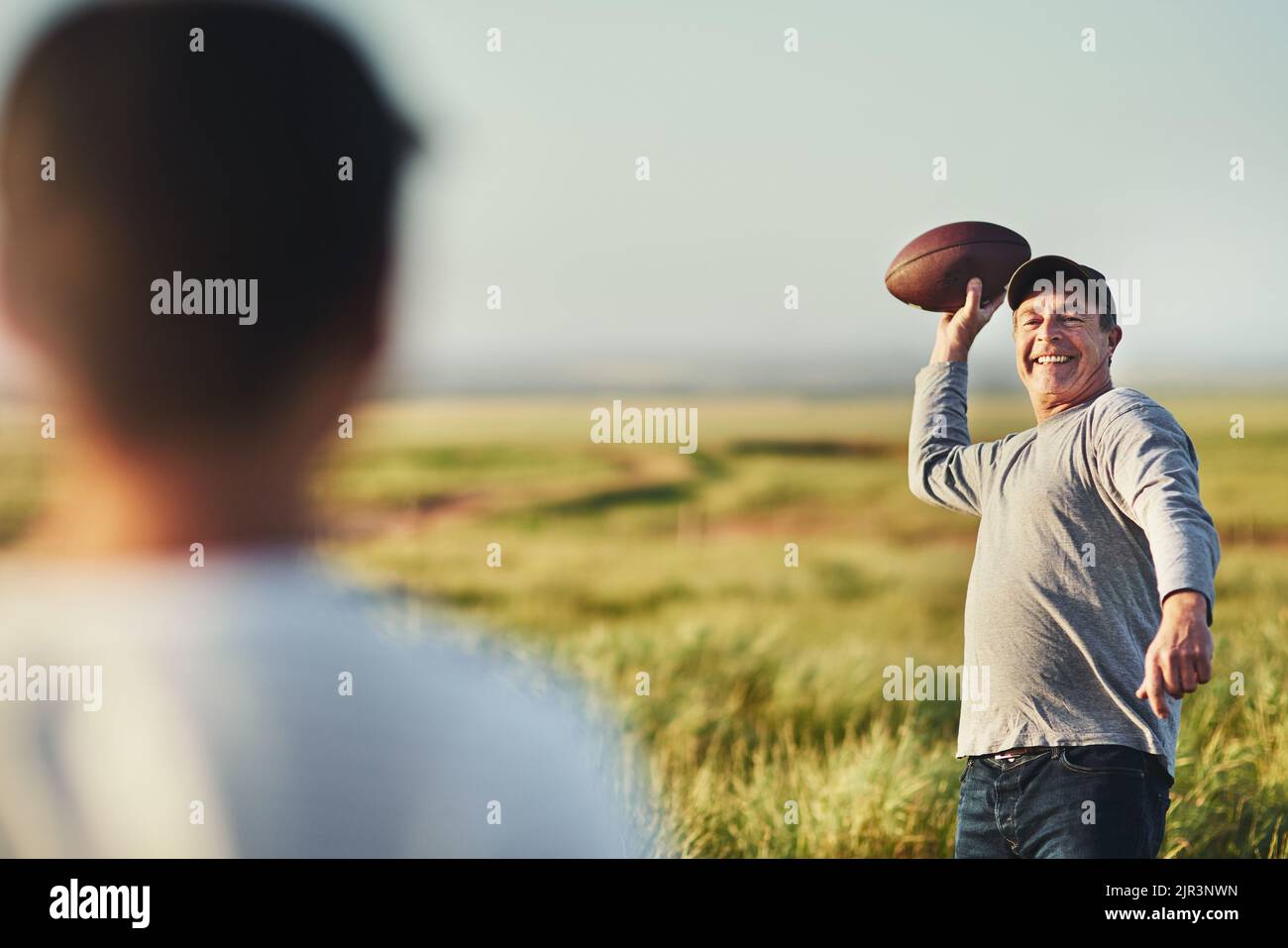 Mal sehen, ob Sie diese auch fangen können. Vater wirft einen Fußball zu seinem Sohn auf einem Feld. Stockfoto