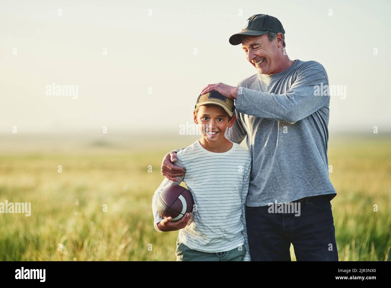 Papa hat mir alles beigebracht, was ich über Fußball wissen muss. Vater und Sohn spielen mit einem Fußball auf einem Feld. Stockfoto