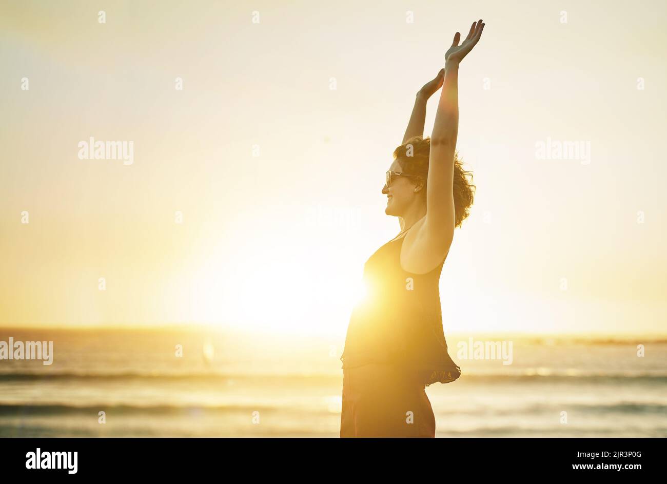 Leuchtet heller als die Sonne. Eine junge Frau mit ihren Armen am Strand. Stockfoto