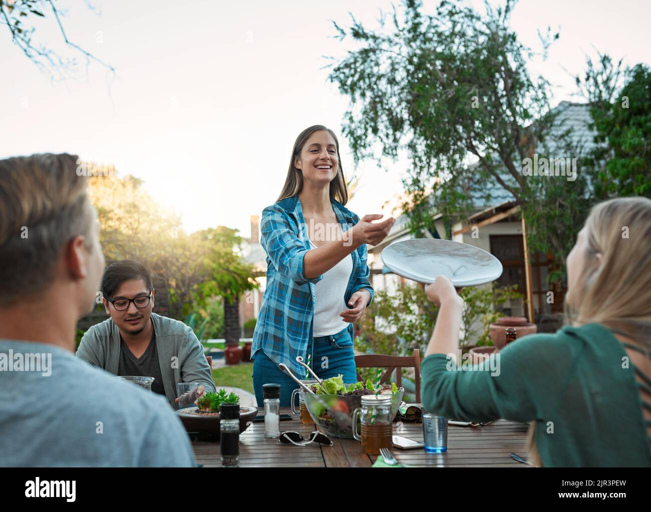 Why Danke. eine junge Gruppe von Freunden, die zusammen ein Essen genießen, während sie draußen an einem Tisch im Garten sitzen. Stockfoto