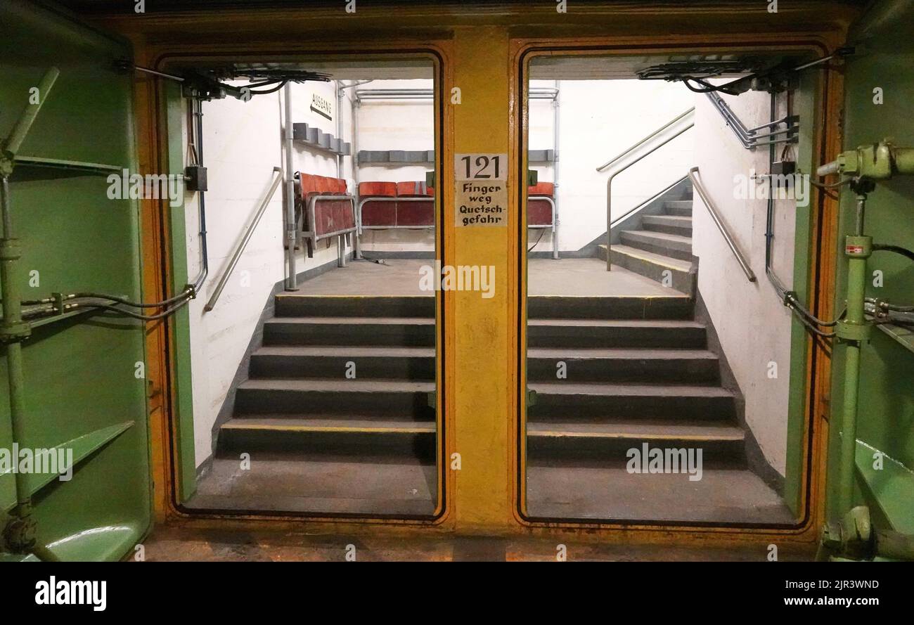 Hamburg, Deutschland. 25.. Juli 2022. Einer der Eingänge zum unterirdischen Bunker Steintorwall ist offen. Dahinter sind Sitzreihen und eine Treppe zu sehen. Die 140 Meter lange und 17 Meter breite Anlage in der Nähe des Hauptbahnhofs wurde von 1941 bis 1943 gebaut. Während des Kalten Krieges wurde es in einen Atombunker umgewandelt und hätte im Notfall 2700 Menschen Schutz geboten. Seit 2007 organisiert der Verein Hamburger Unterwelten Führungen und kulturelle Veranstaltungen im unterirdischen Bunker, damit die Geschichte dieses Ortes nicht vergessen wird. Quelle: Julian Weber/dpa/Alamy Live News Stockfoto