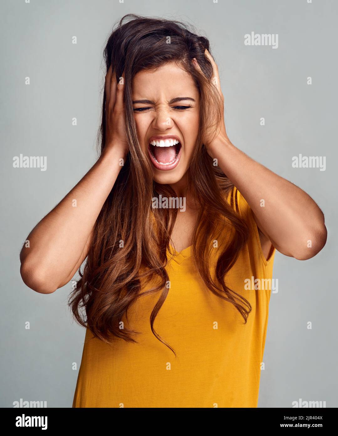 Hört mich brüllen. Studioaufnahme einer attraktiven jungen Frau, die vor grauem Hintergrund schrie. Stockfoto