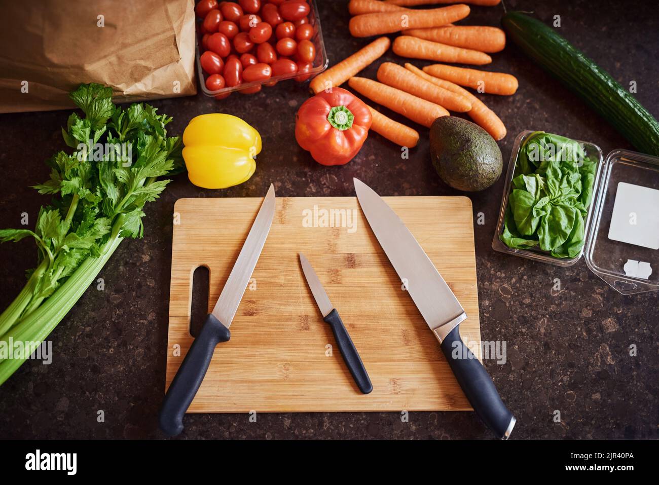 Überspringen Sie Ihre Ernährung, nur gesund essen. Eine Aufnahme aus einer Auswahl frischer Zutaten, die auf einem Schneidebrett auf einer Küchentheke angeordnet sind. Stockfoto