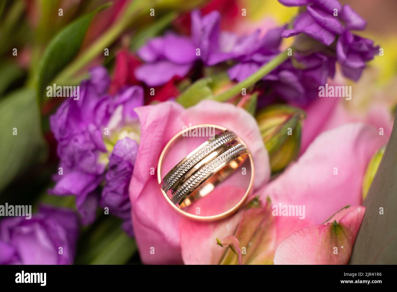 Hochzeit Goldringe der Braut und des Bräutigams liegen auf dem Hintergrund eines Blumenstraußes der Braut, Goldringe bei der Hochzeit Stockfoto