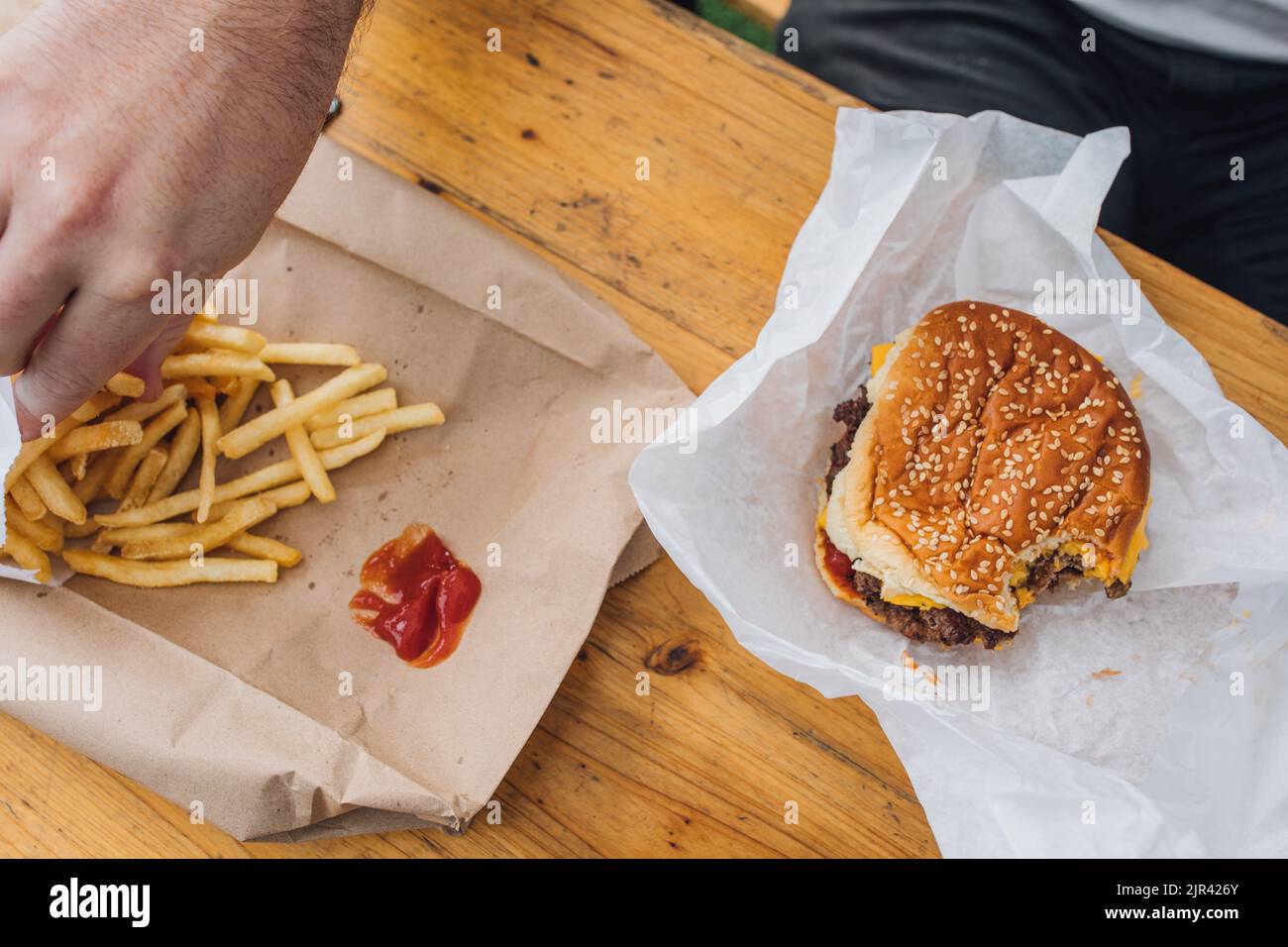 Mann, der Pommes mit Ketchup und Cheeseburger isst Stockfoto