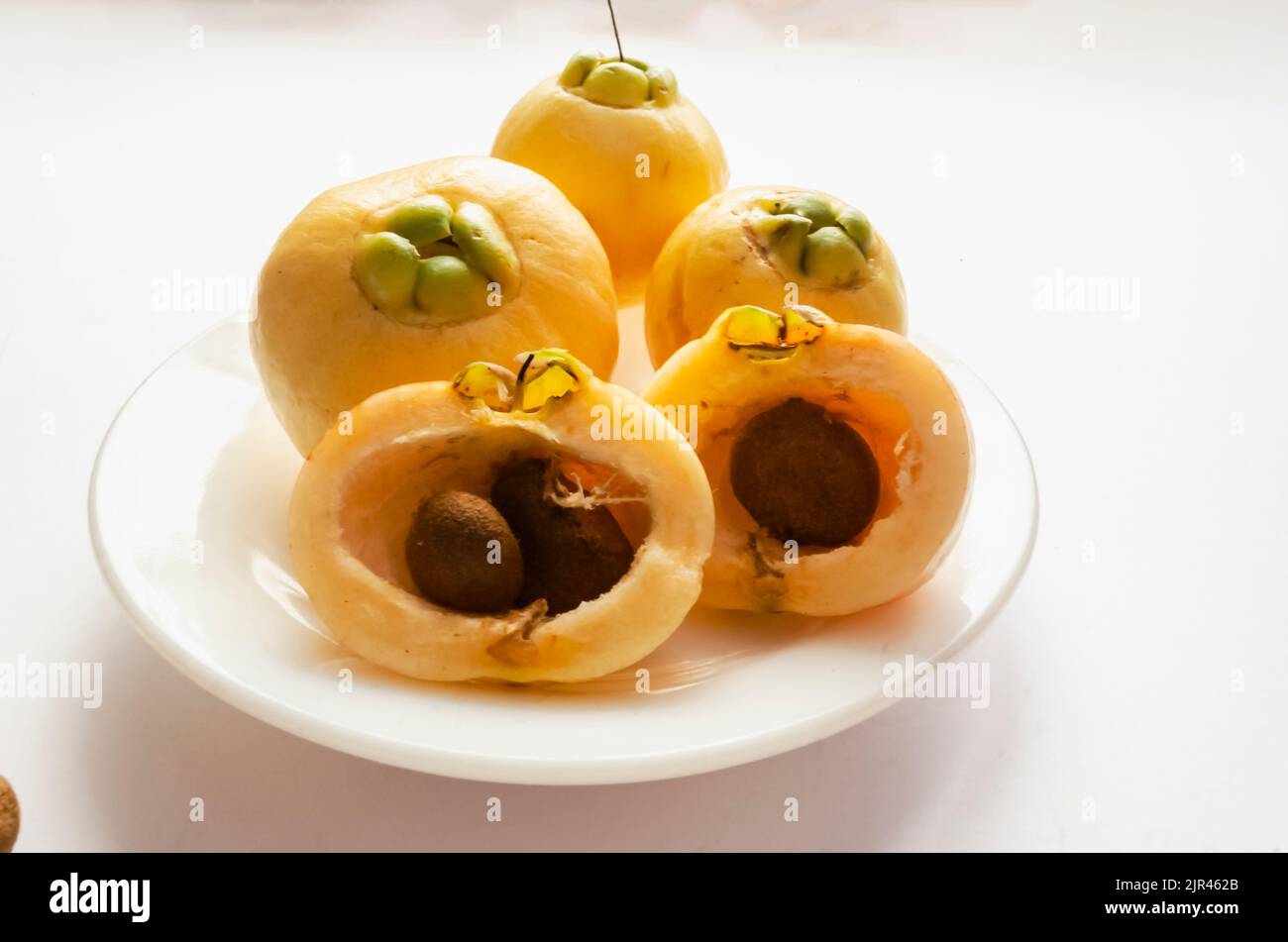 Ganze und halbiert Rosenäpfel mit Samen in Einem weißen Teller Stockfoto