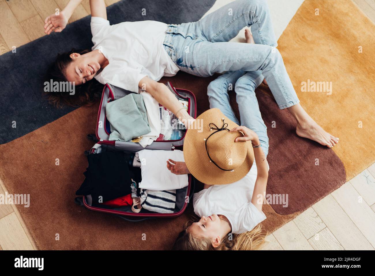Mutter und Tochter träumen von einer Reise, liegen auf dem Boden und packen einen Koffer. Stockfoto