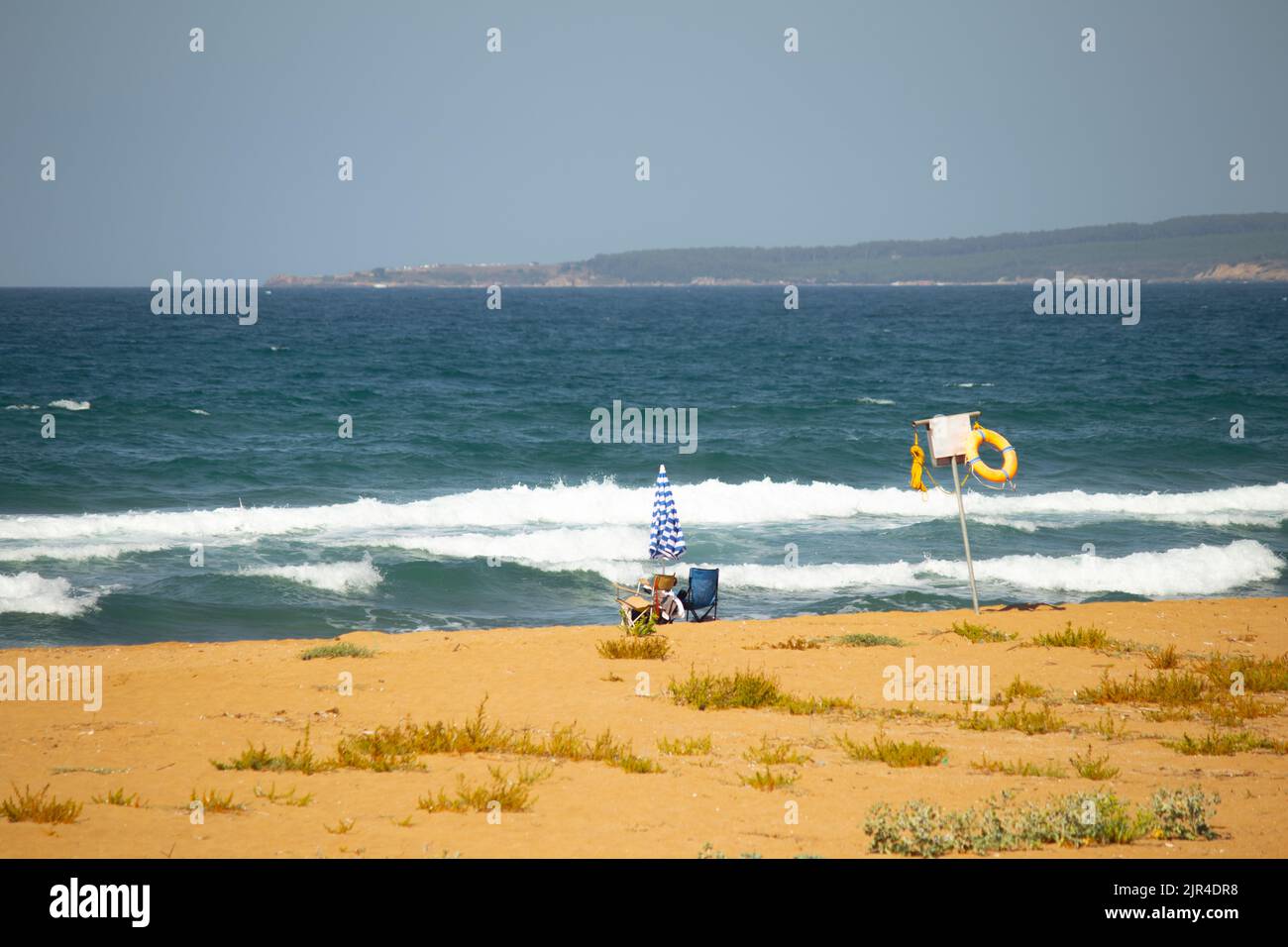 Einsames Strandfoto mit Vintage-Farben. Leere Küstenwarnschild mit Sonnenschirm und zwei Liegestühlen. Kopfruhebereich weg von Menschen. Stockfoto