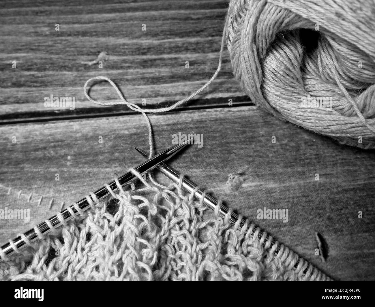 Durchbrochene Tischdecke beim Stricken. Stricknadeln, Schlaufen auf Stricknadeln, Strickstoff, Fadenknäuel, grobe Baumwolle und Leinen Stockfoto