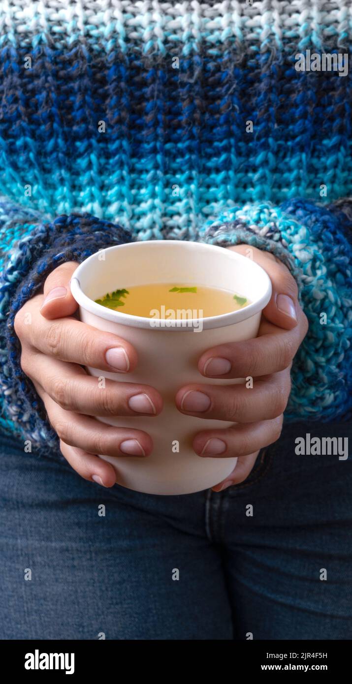 Hände mit einer Tasse zum Mitnehmen und Hühnerbrühe Stockfoto