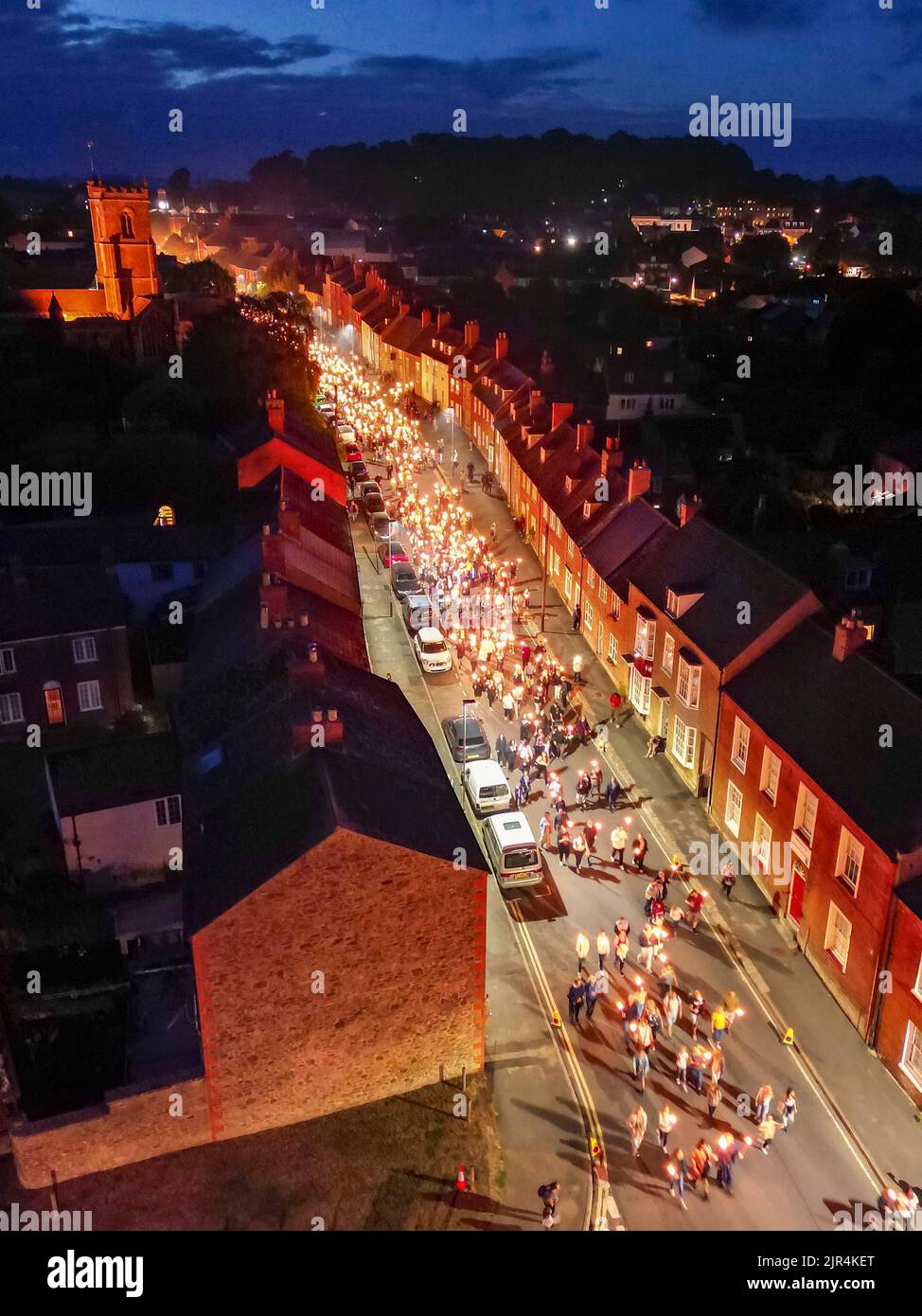 Bridport, Dorset, Großbritannien. 21.. August 2022. Blick aus der Luft, während Hunderte von Feiernden zur jährlichen Bridport Carnival Fackelparade in Bridport in Dorset kommen, die nach drei Jahren Abwesenheit aufgrund der Covid-19-Pandemie zurückkehrt. Die Fackelparade geht vom Rathaus in Bridport nach East Beach in West Bay. Bildnachweis: Graham Hunt/Alamy Live News Stockfoto
