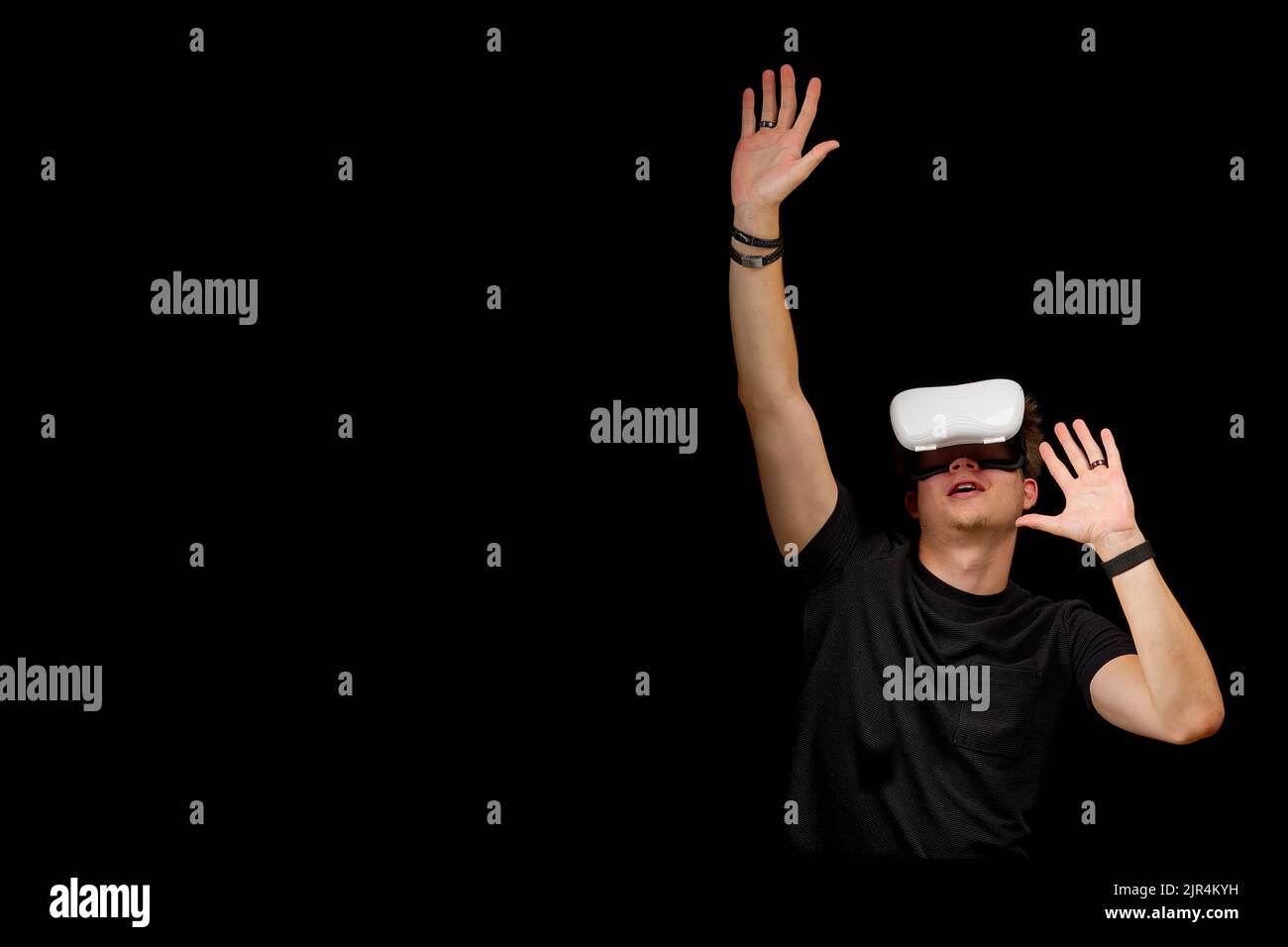 Junger Mann trägt Virtual Reality VR-Brille, Brille isoliert auf schwarzem Hintergrund. In Einer Metaverse Stockfoto