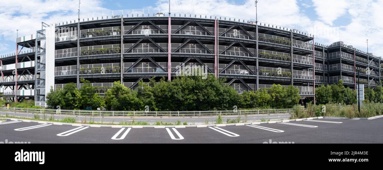 Ein Panoramablick auf das Äußere einer 6-stöckigen Parkgarage, eines Parkplatzes oder einer Parkade in der EON Mall, die während der Sommerferien mit Autos gefüllt ist. Stockfoto