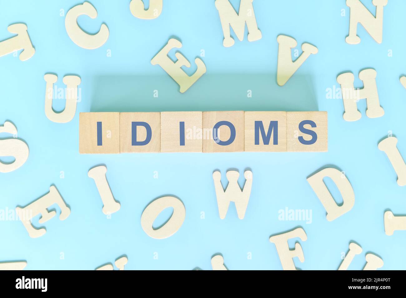 Idiome oder Idiom Konzept in Englisch Grammatik Unterricht. Holzblöcke Typografie flach lag in blauem Hintergrund. Stockfoto
