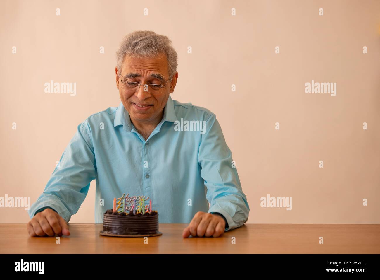 Trauriger älterer Mann, der seinen Geburtstag einsam zu Hause feiert Stockfoto