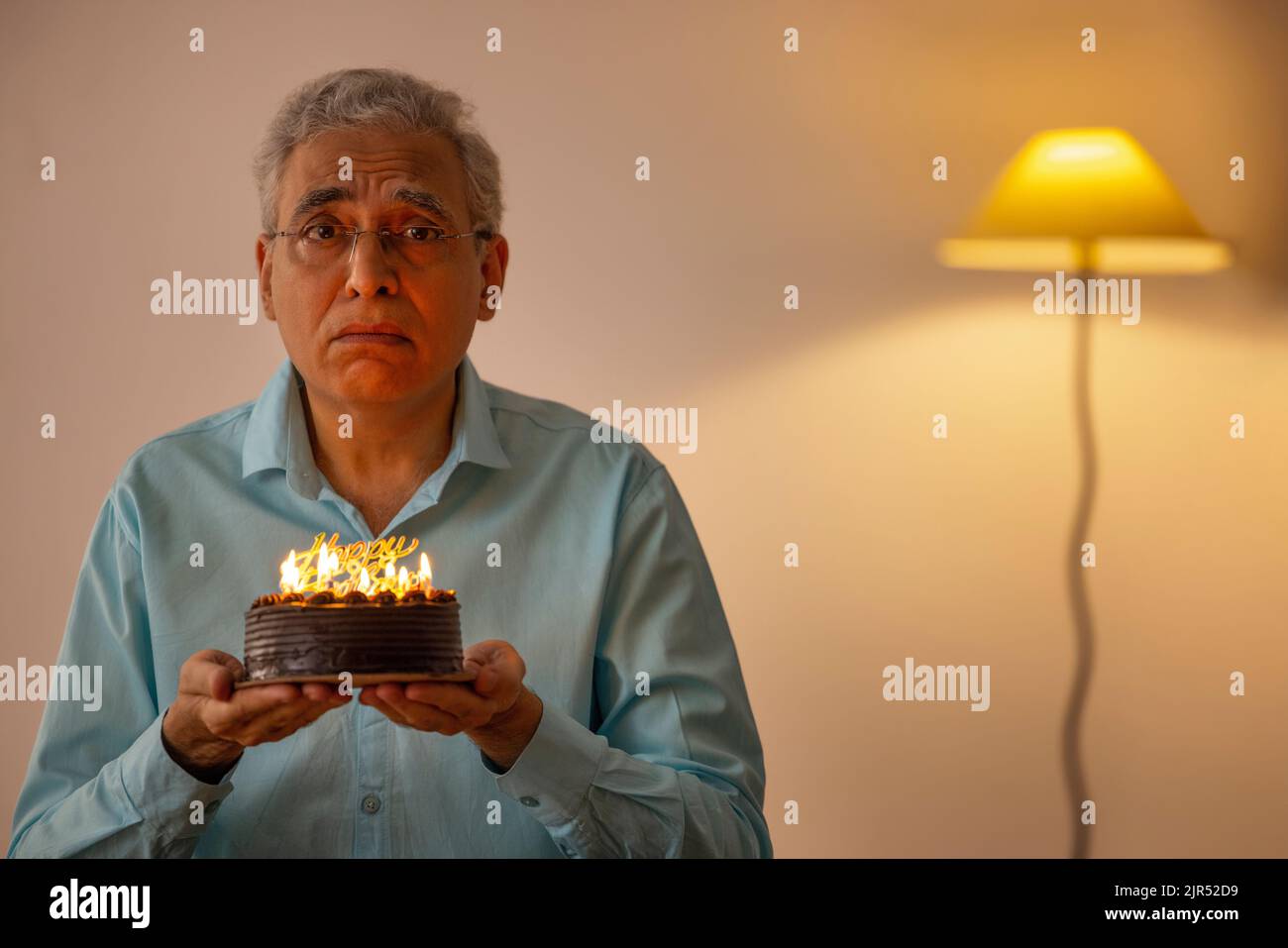 Trauriger älterer Mann, der seinen Geburtstag einsam zu Hause feiert Stockfoto