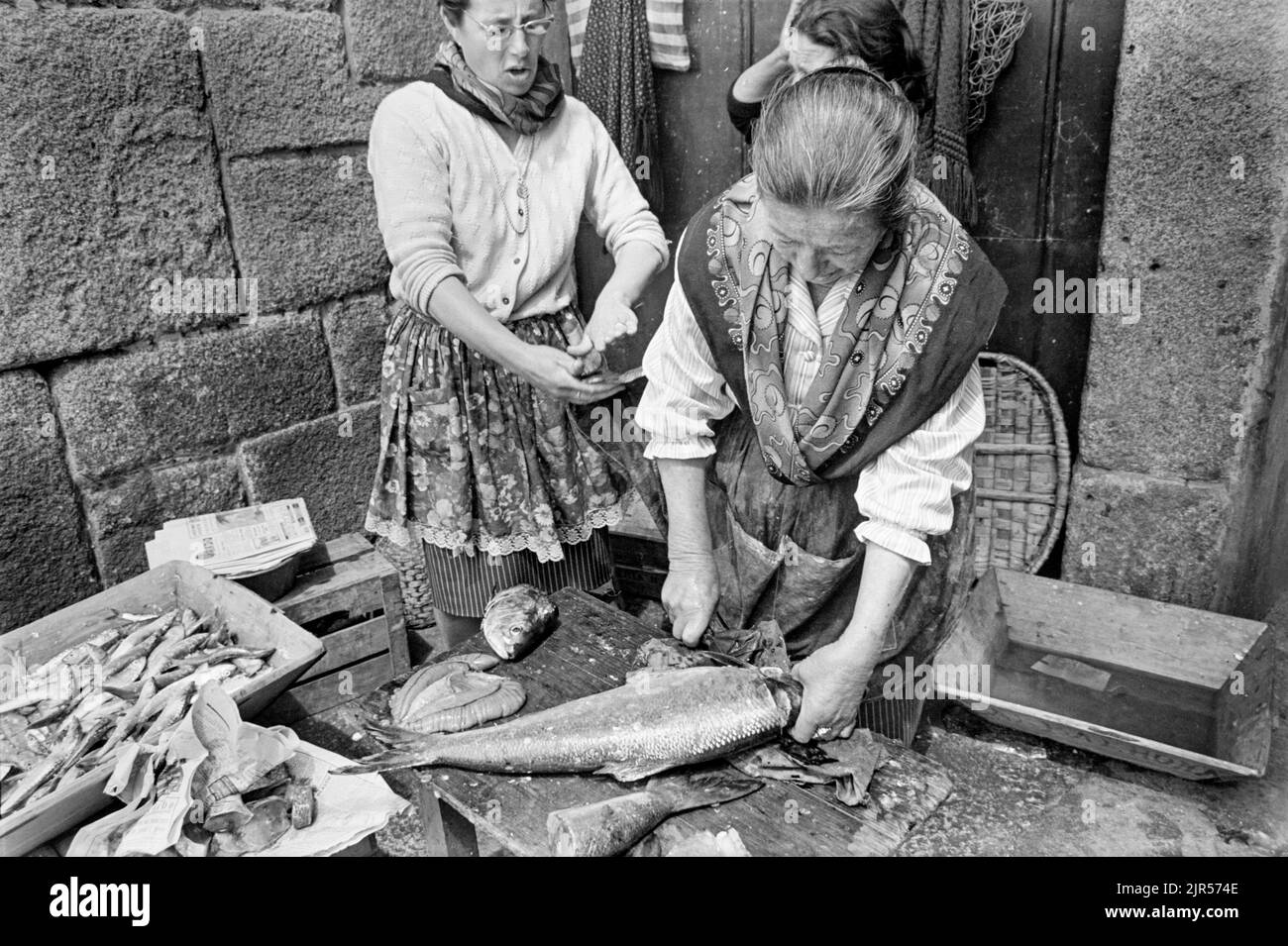 PORTUGAL - PORTO - 1970. Frauen, die Fische auf einem Markt am Fluss im Bezirk Ribeira von Porto, Nordportugal, ausschneiden und zubereiten. Copyright Ph Stockfoto