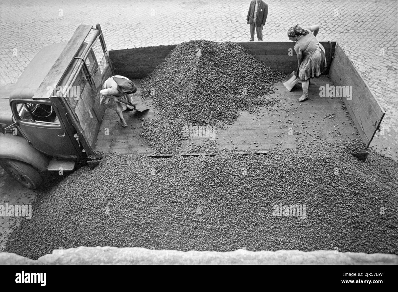PORTUGAL - PORTO - 1970. Frauen, die Kohle von einem Lastwagen auf der Uferpromenade des Douro im Bezirk Ribeira in Porto, Nordportugal, entladen. Cop Stockfoto