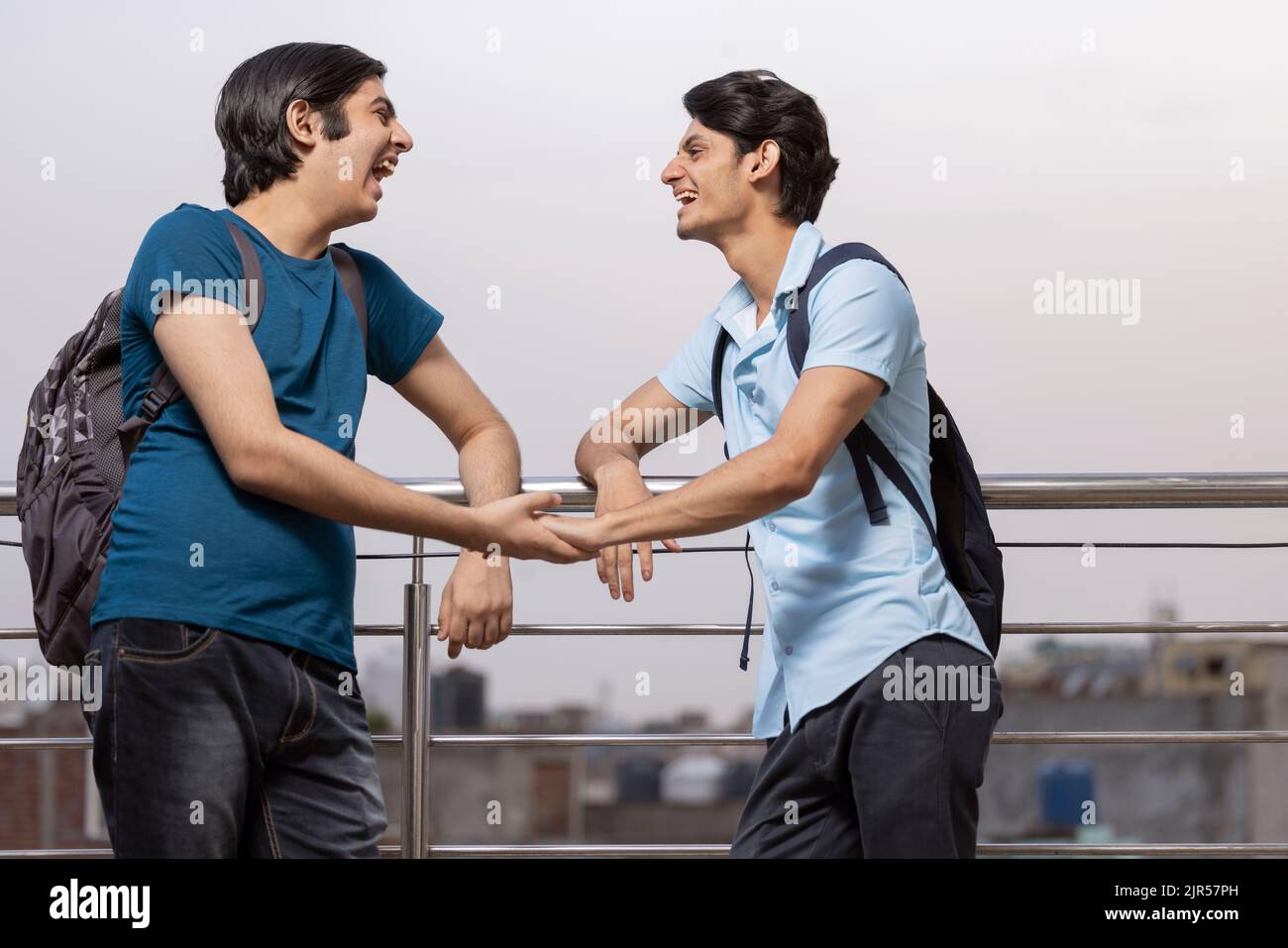 Zwei Teenager-Freunde sprechen, während sie am Geländer zusammenstehen Stockfoto