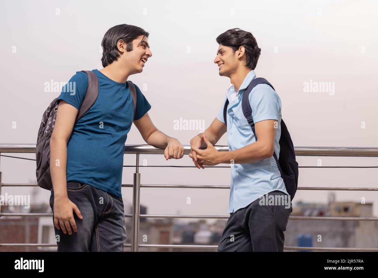 Zwei Teenager-Freunde sprechen, während sie am Geländer zusammenstehen Stockfoto