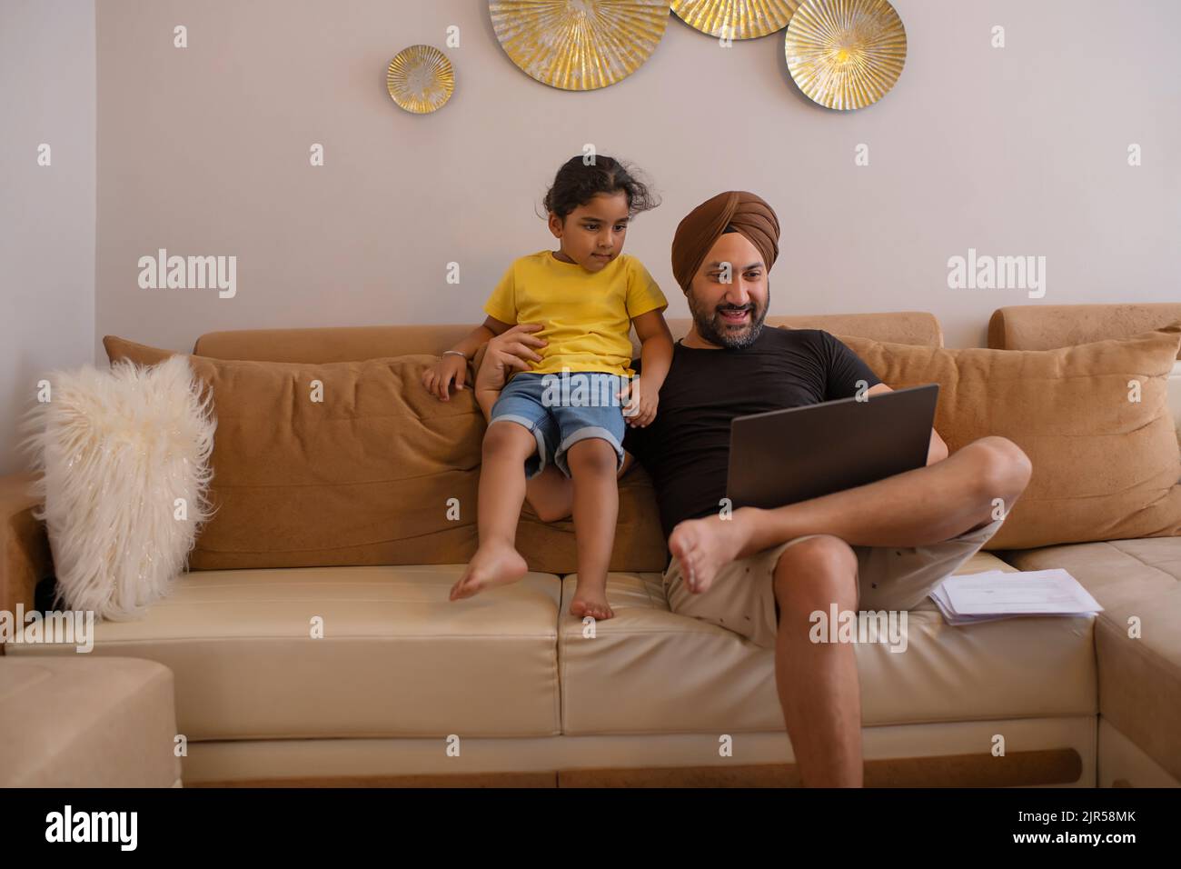 Vater und Tochter schauen sich im Wohnzimmer Cartoons auf dem Laptop an Stockfoto