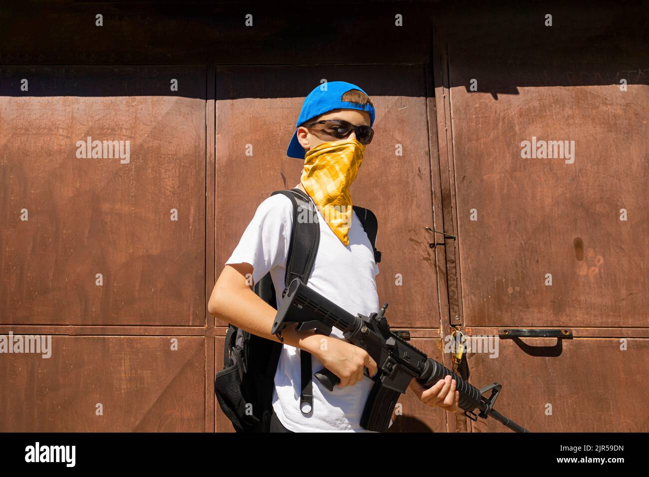 Bewaffneter minderjähriger Mann mit Bandana und Sonnenbrille Stockfoto
