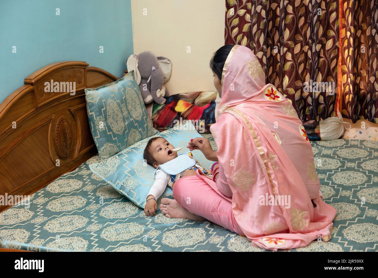 Mutter füttert ihr Baby mit einem Löffel auf dem Bett Stockfoto