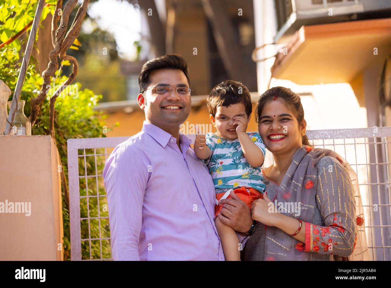 Porträt eines glücklichen Paares mit dem Kind, das vor dem Tor steht Stockfoto