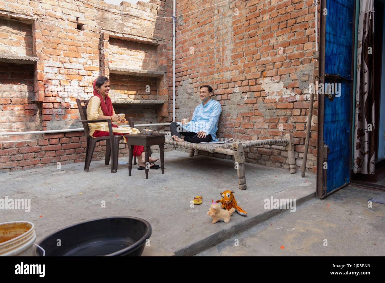 Junges Paar, das sich unterhielt, während es im Hinterhof Tee tranken und sich unterhielt Stockfoto
