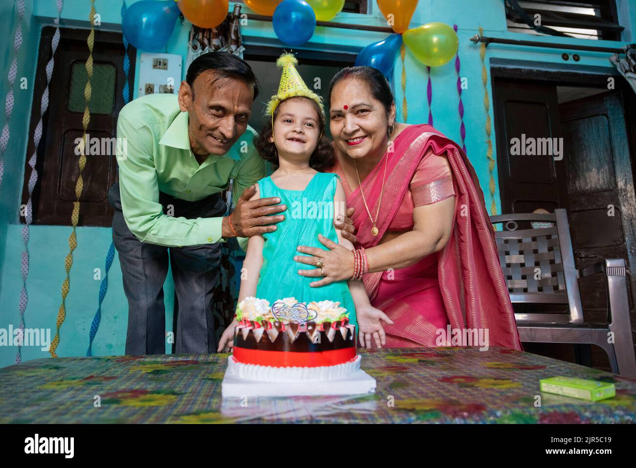 Porträt eines glücklichen kleinen Kindes mit ihrer Großelternin und Geburtstagskuchen Stockfoto