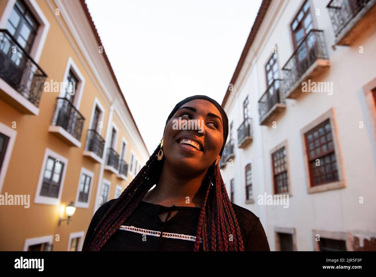 Sao Luis do Maranhao, Maranhao, Brasilien - 18. Mai 2016: Junge Afro-Frau lächelt inmitten der Kolonialhäuser des historischen Zentrums von Sao Luis. Stockfoto