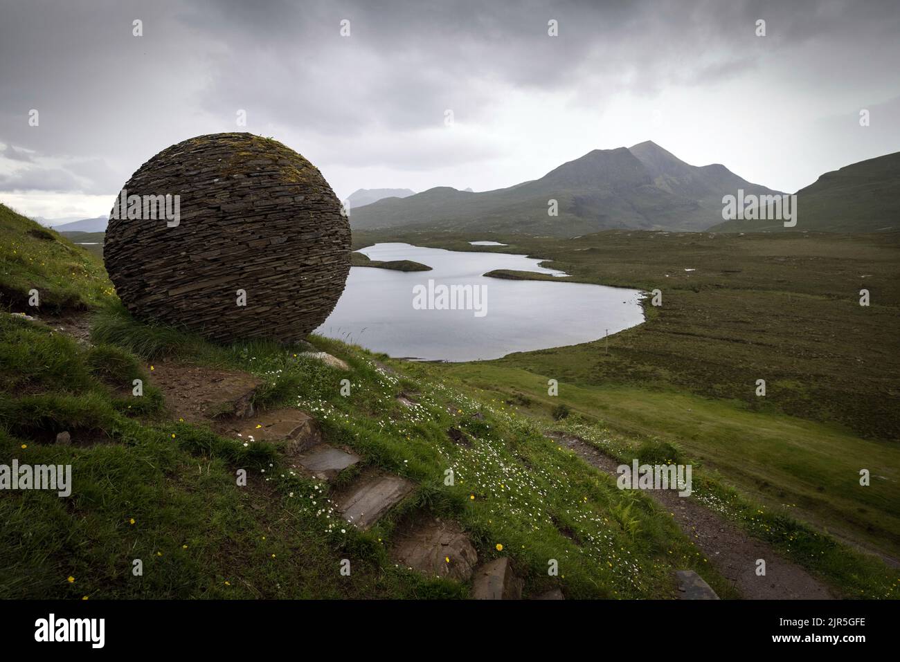 Joe Smiths Steinskulptur The Globe am Knockan Crag in Assynt im Nordwesten der Highlands überblickt Lochan an AIS mit den Gipfeln von Cùl Beag Stockfoto