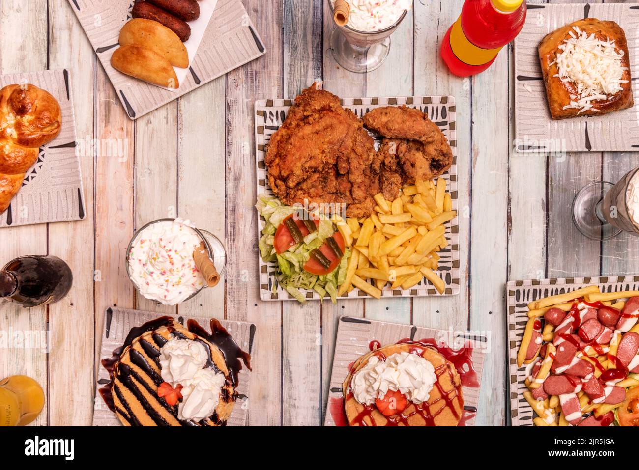 Set von Fast-Food-Gerichten mit Huhn im Teig mit Kartoffeln und Salat, Pfannkuchen mit Schokolade und Erdbeersirup, viel Creme und Knödel Stockfoto