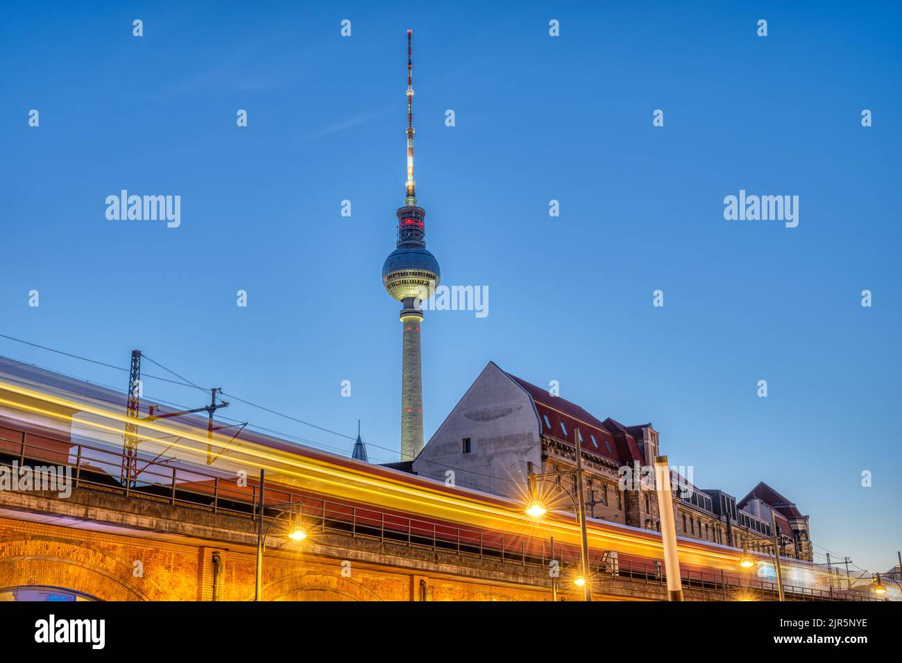 Die berühmten Fernsehturm in Berlin in der Dämmerung mit einem unscharfen S-Bahn Stockfoto