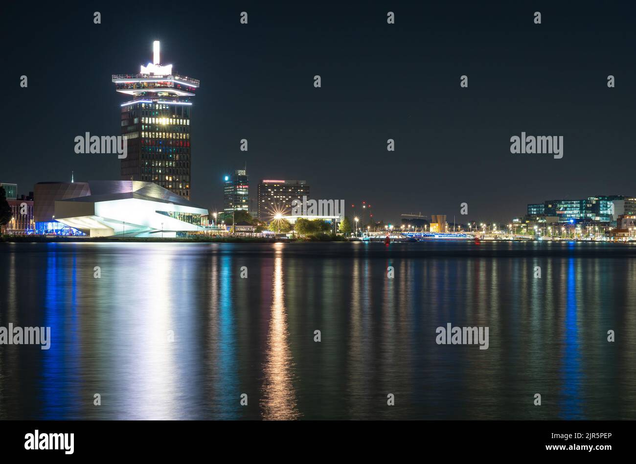 Skyline von Amsterdam bei Nacht, moderne Gebäude am IJ-Fluss Stockfoto