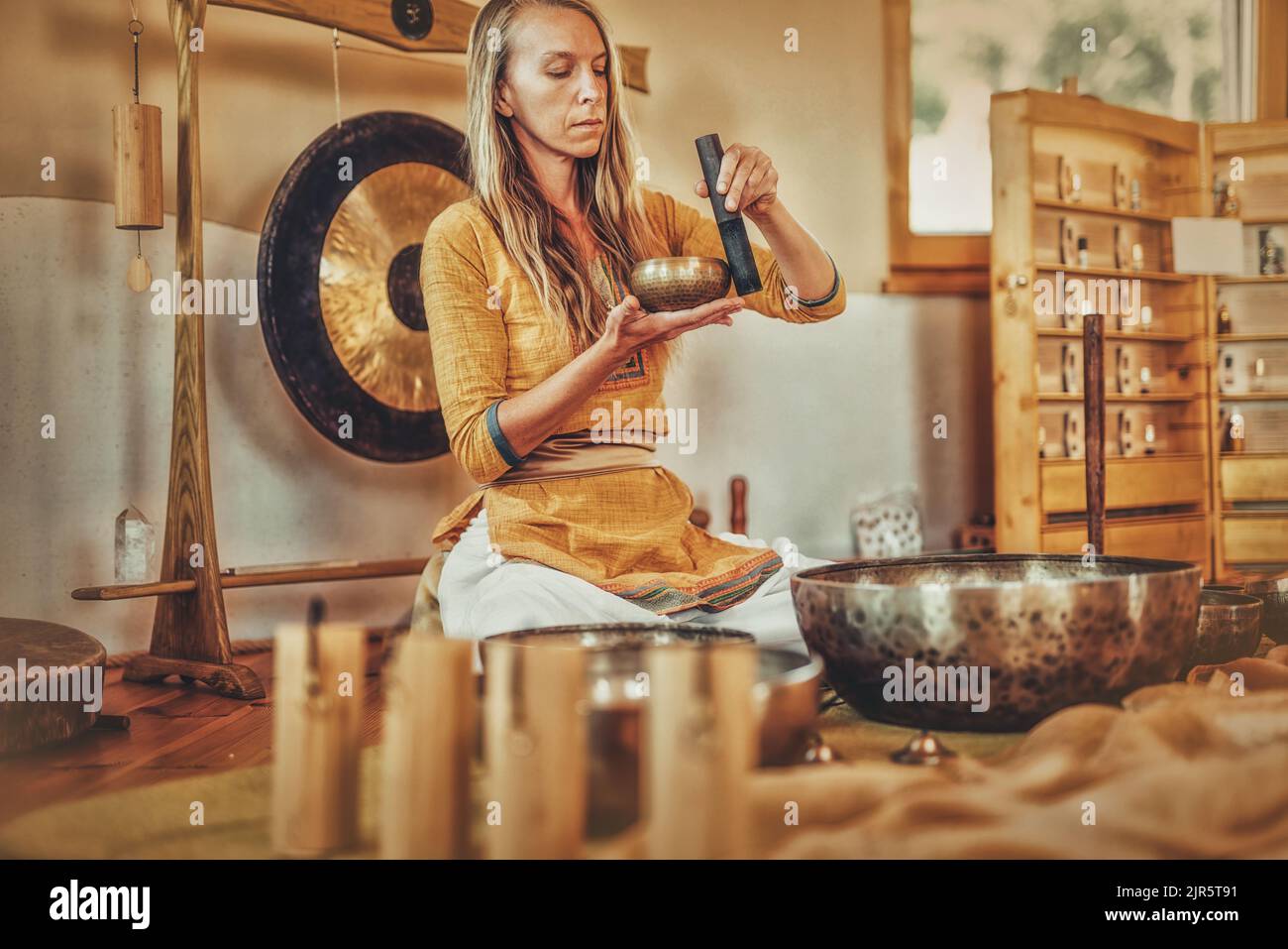 Schöne Frau spielt auf tibetischer Schale, zeremonieller Raum. Stockfoto