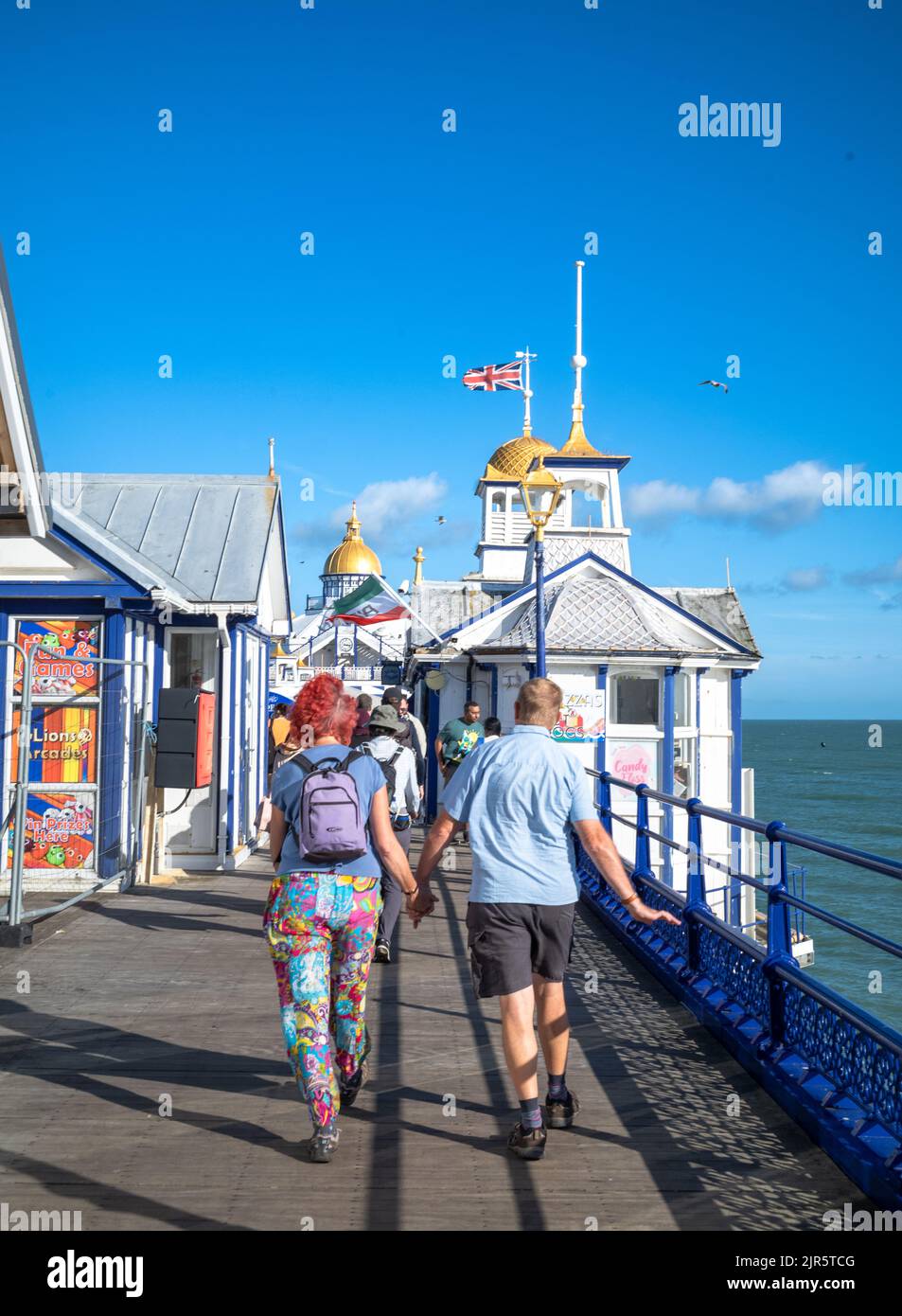Ein Paar geht Hand in Hand den Eastbourne Pier, East Sussex, Großbritannien, entlang. Stockfoto