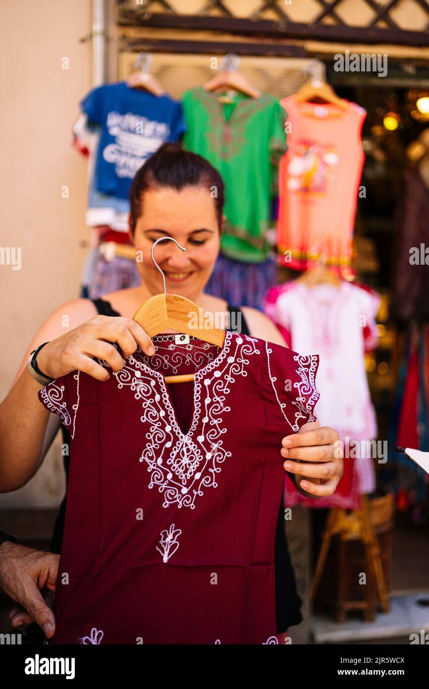 Eine junge Frau, die auf einem Straßenmarkt Kleidung zeigt. Stockfoto