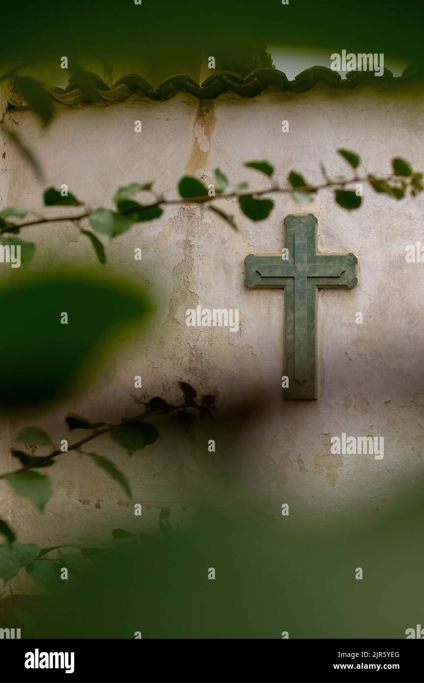 Cross Religion. Symbol. Verehrung. Kreuz auf abgenutzten Wand zwischen Vegetation, Pflanze aus dem Fokus und Fliesen auf der Oberseite, mexiko Stockfoto