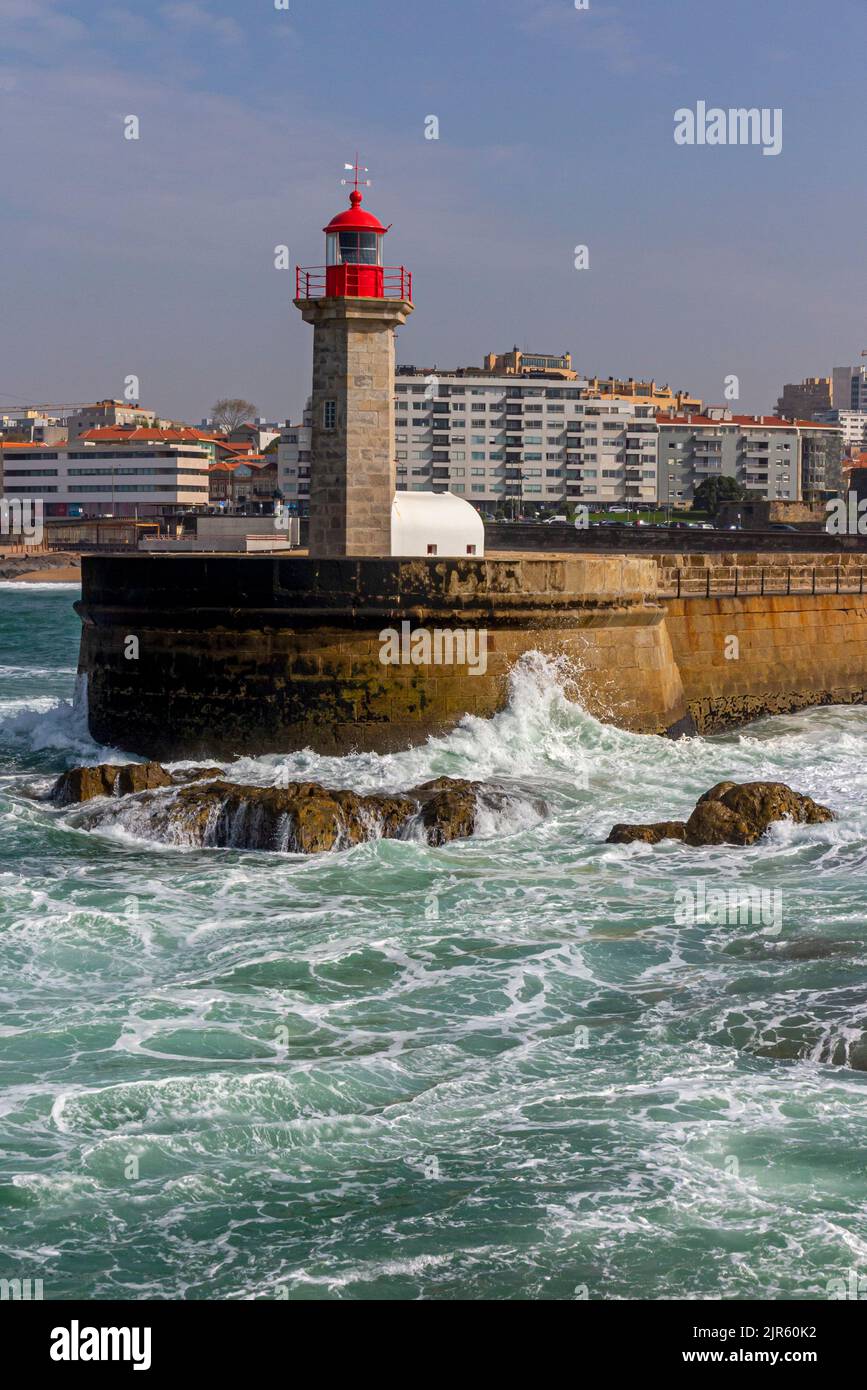 Wellen schlagen gegen die Basis des Leuchtturms Farol das Felgueiras in Foz do Douro in der Nähe von Porto im Norden Portugals. Stockfoto